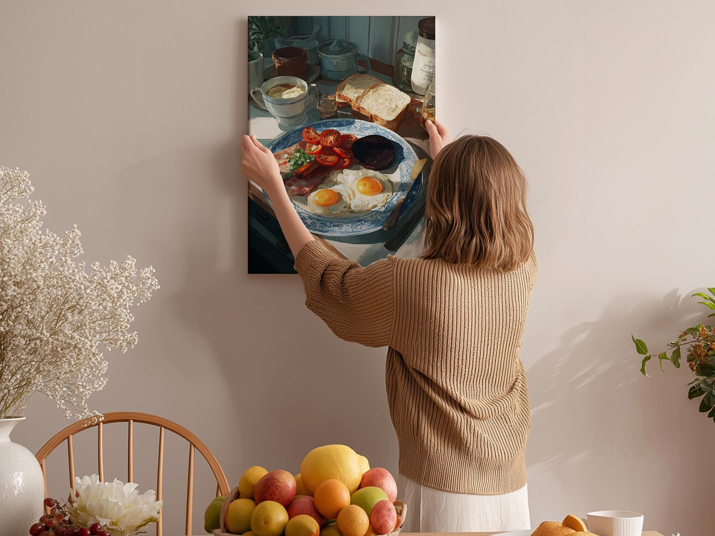 A woman hangs a framed photograph of a breakfast scene on a wall in a cozy kitchen.