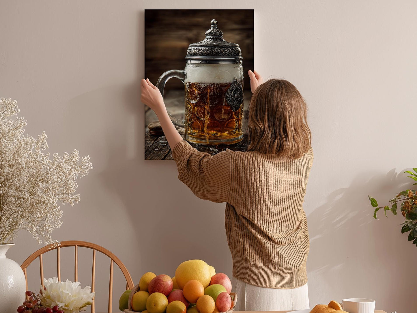 A woman hangs a framed photograph of a glass mug filled with beer on a wall in a cozy kitchen setting.