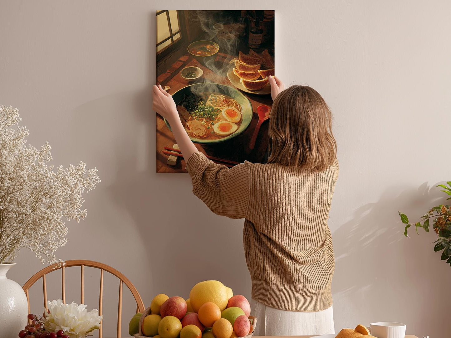 A woman hangs a framed picture of a meal on a wall, featuring a bowl of food and a plate of toast.