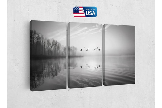 a black and white photo of birds flying over a lake