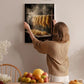 A woman hangs a framed photograph of noodles on a wall in a cozy kitchen setting.