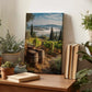 a wooden table with a framed landscape photograph of a vineyard, surrounded by potted plants and books.