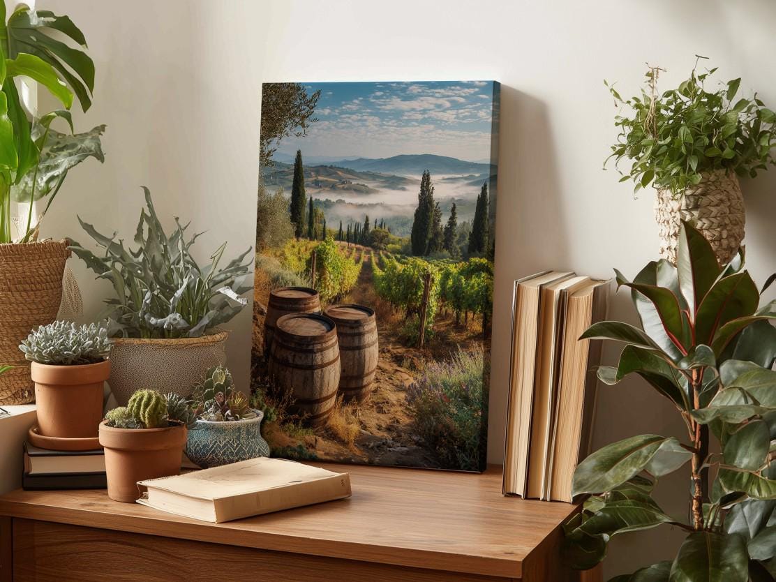 a wooden table with a framed landscape photograph of a vineyard, surrounded by potted plants and books.