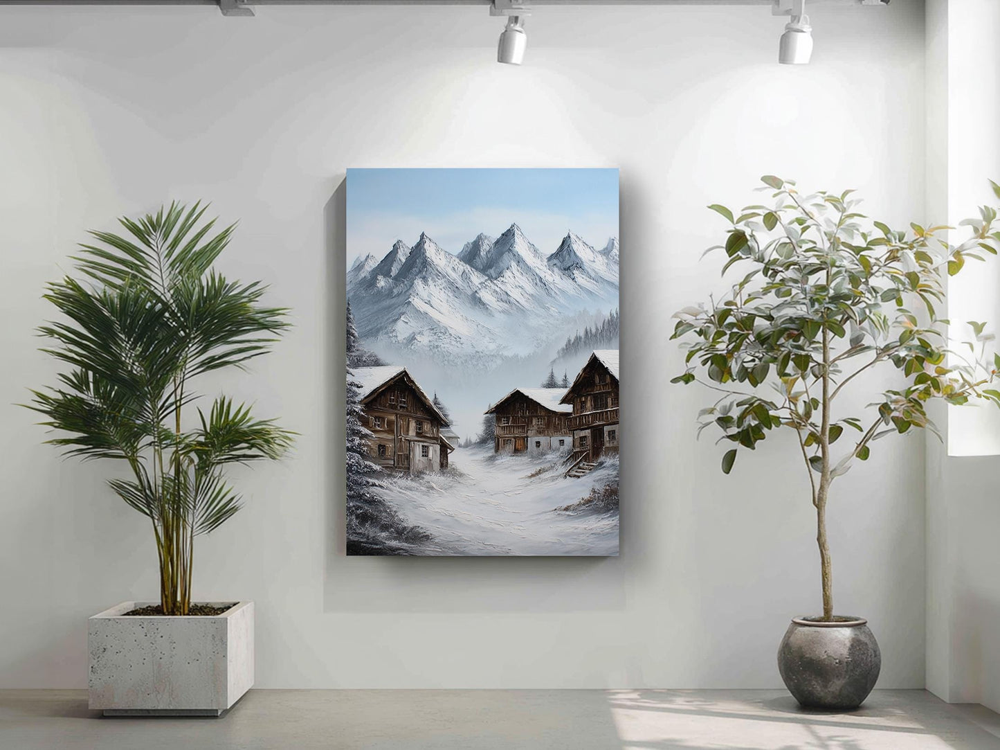 a painting of a snowy mountain village with two houses, one on each side of the mountain, surrounded by snow-covered trees. The painting is hung on a white wall, and there are two potted plants in the foreground, one on the left and one on the right.
