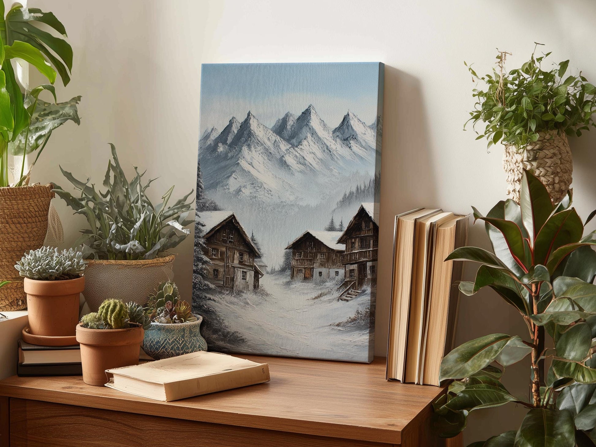 a wooden table with a painting of a snowy mountain village, surrounded by potted plants and books.