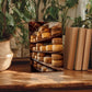 a wooden table with a framed photograph of a cheese rack, surrounded by potted plants and books.