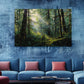 a large painting of a lush forest scene hanging on a blue wall above a blue sofa with red throw pillows.