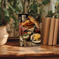 a wooden table with a framed painting of a breakfast scene, including croissants, cheese, and other food items. The painting is surrounded by potted plants and books, creating a cozy and inviting atmosphere.