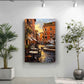 a painting of a street scene with buildings, tables, and chairs, hanging on a wall.