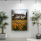 a large painting of a house surrounded by a field of sunflowers, with a blue sky and clouds in the background.