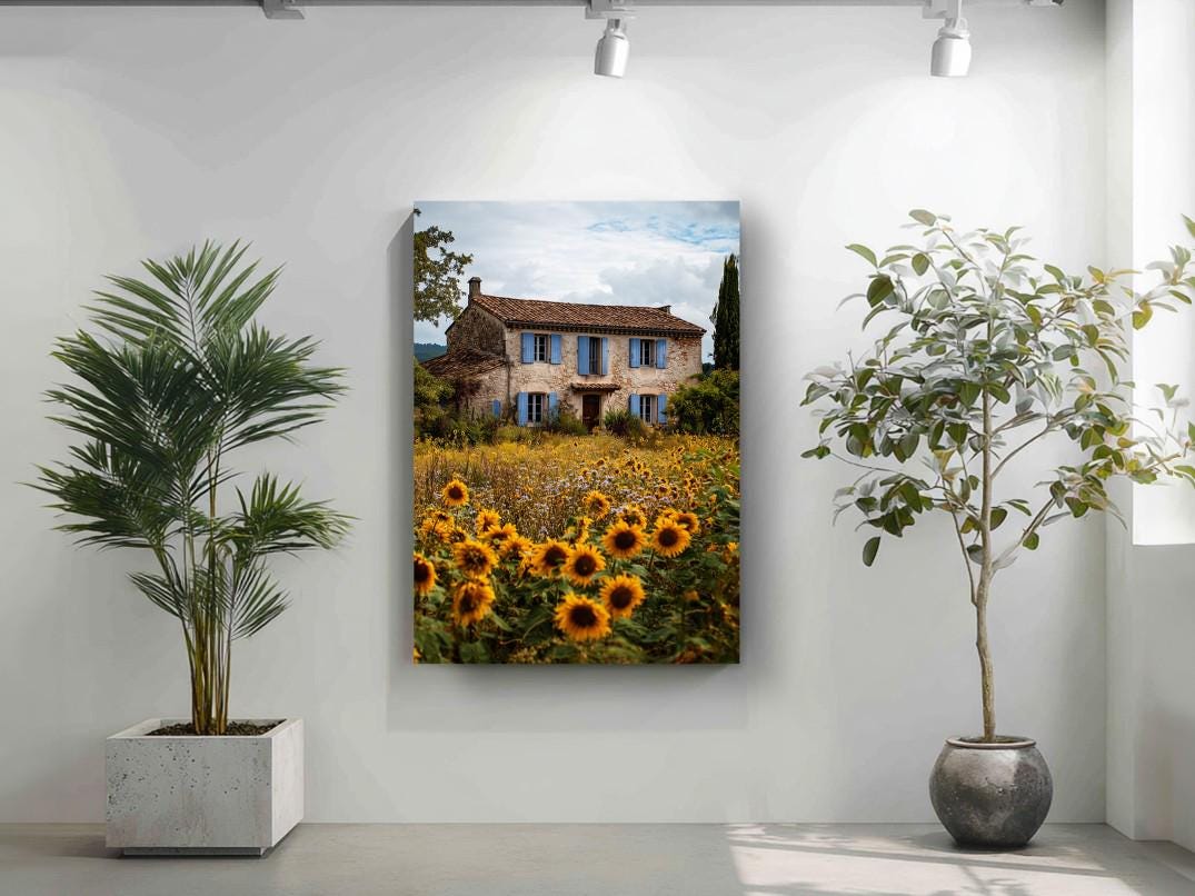 a large painting of a house surrounded by a field of sunflowers, with a blue sky and clouds in the background.