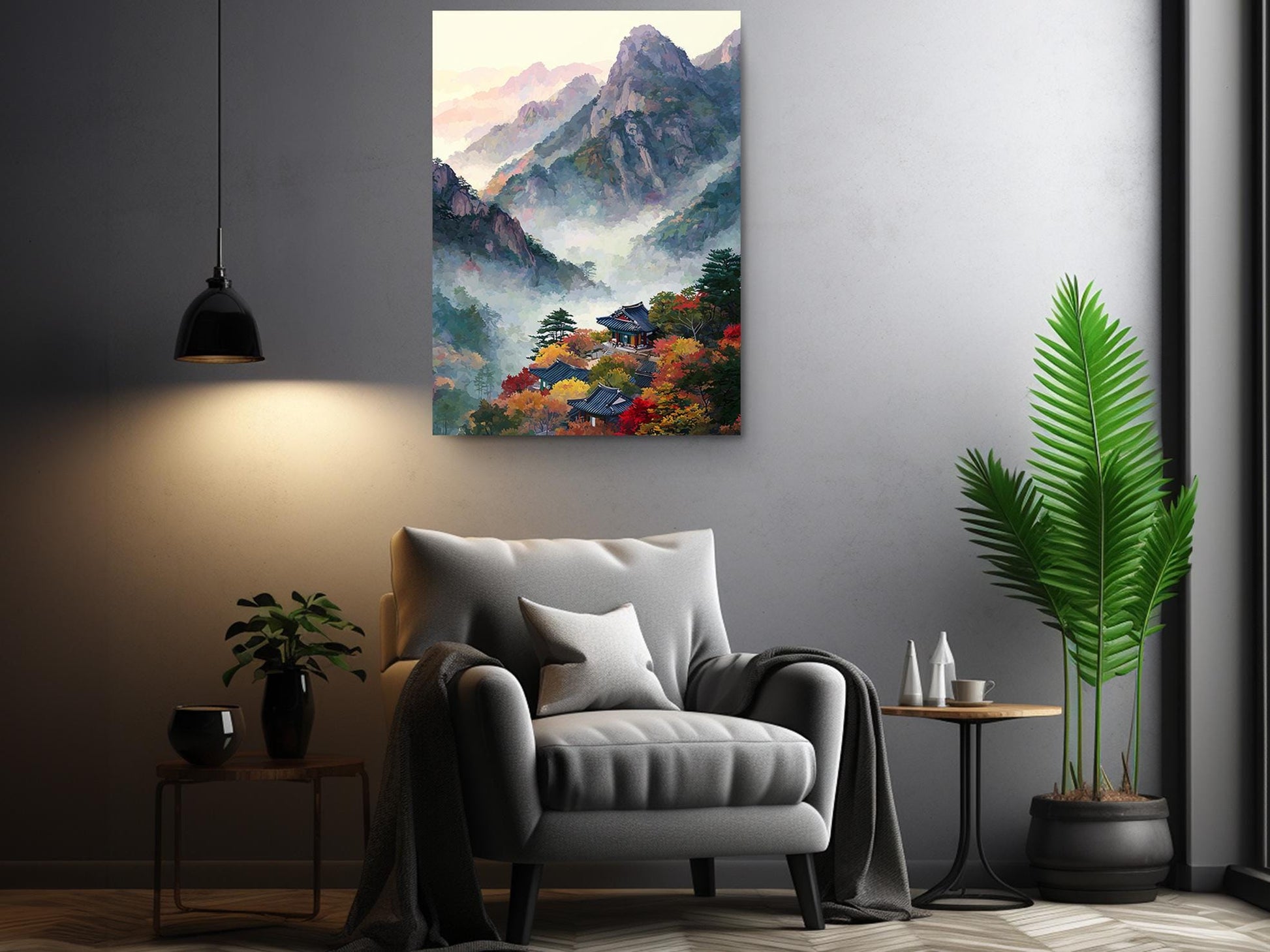 a cozy living room with a gray armchair, a wooden side table, and a potted plant. Above the armchair, there is a large painting depicting a mountainous landscape with a village nestled in the valley. The painting is hung on the wall, creating a serene and inviting atmosphere in the room.