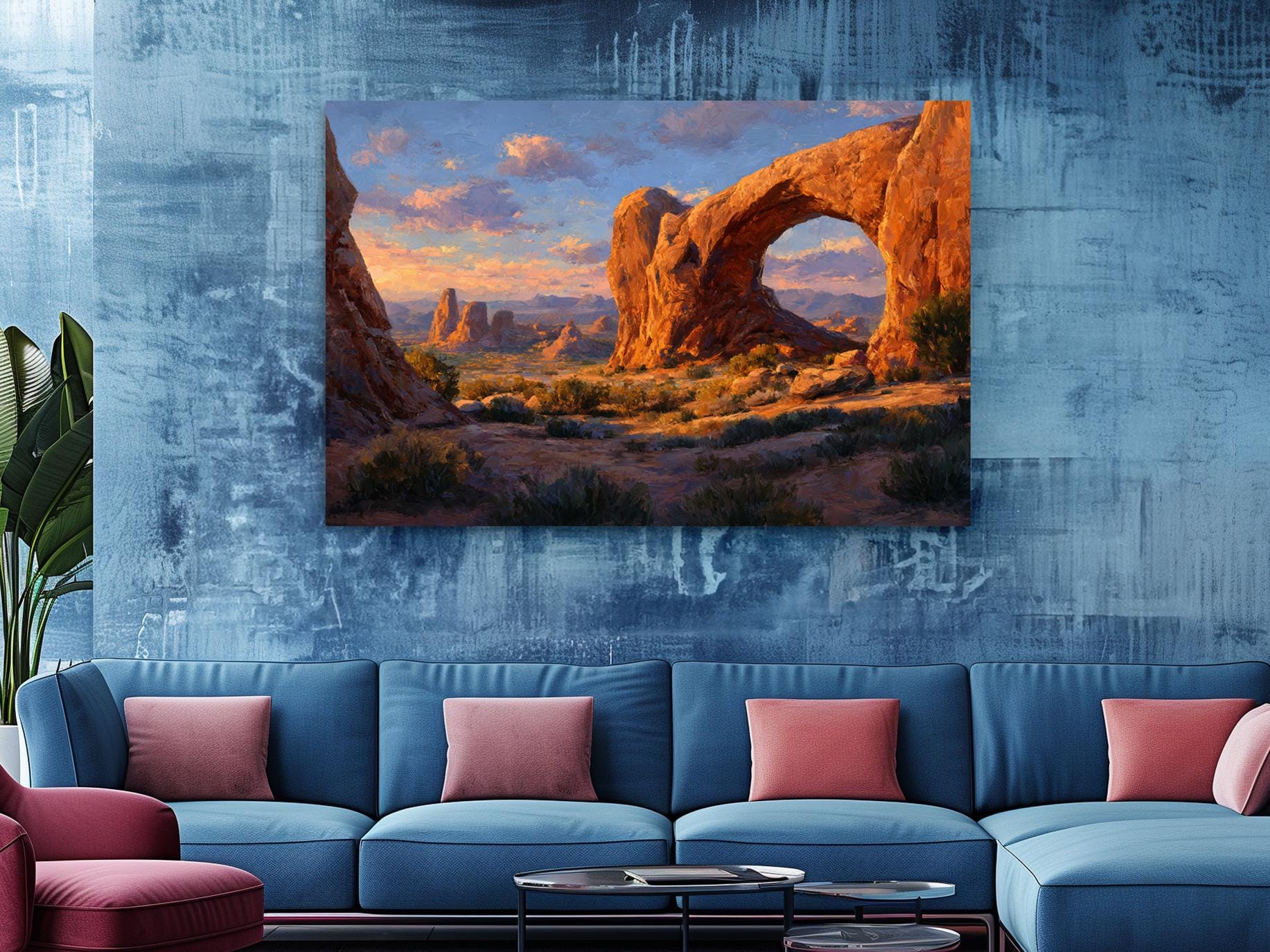 a large, vibrant painting of a desert landscape with a prominent arch formation, hanging on a blue wall above a blue couch with red throw pillows.
