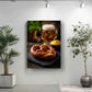 a large framed photograph of a pretzel with a beer mug in the background, placed on a wall in a room with potted plants.