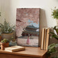 a wooden desk with a framed photograph of a woman in a pink dress standing in front of a traditional Korean palace, surrounded by potted plants and books.
