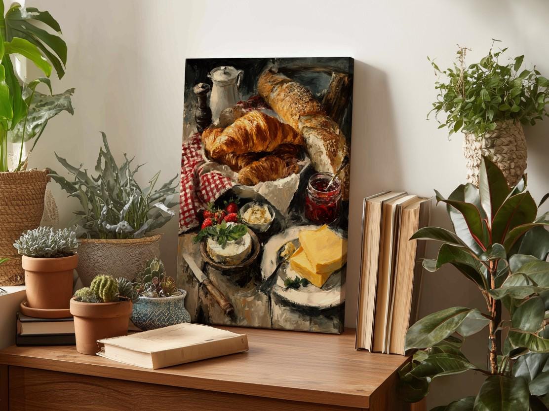 a wooden table with a painting of a table set with food, including croissants, cheese, and strawberries, surrounded by potted plants and books.