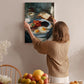 A woman hangs a framed photograph of a breakfast scene on a wall in a cozy kitchen.