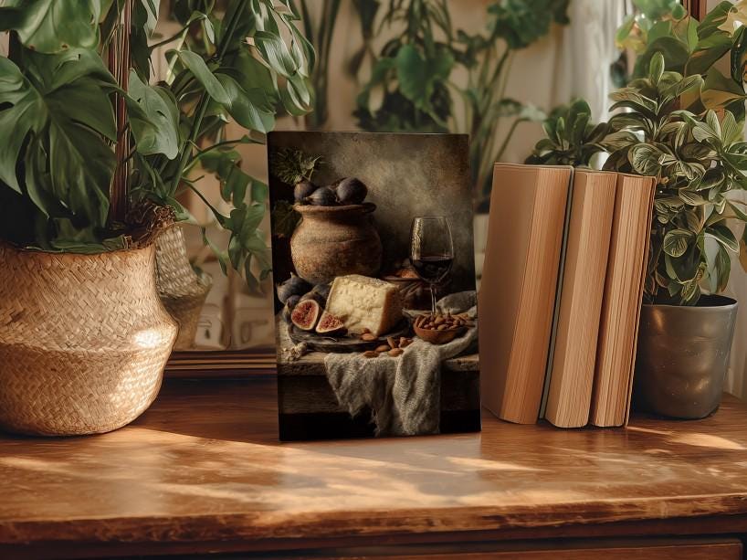 a wooden table with a framed photograph of a still life arrangement, including a vase of flowers, a bowl of fruit, and a book.