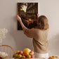 A woman hangs a framed picture of a city street scene on a wall in a cozy, homely setting.