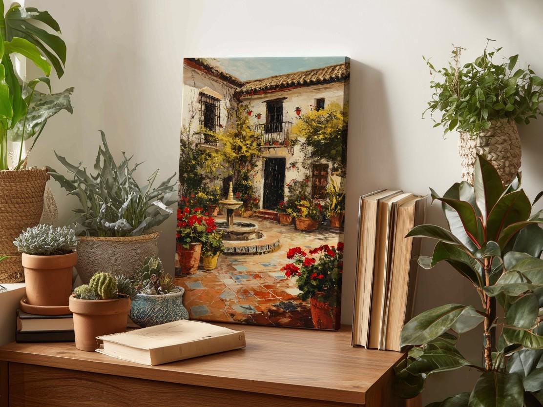 a wooden table with a painting of a courtyard scene, surrounded by potted plants and books.