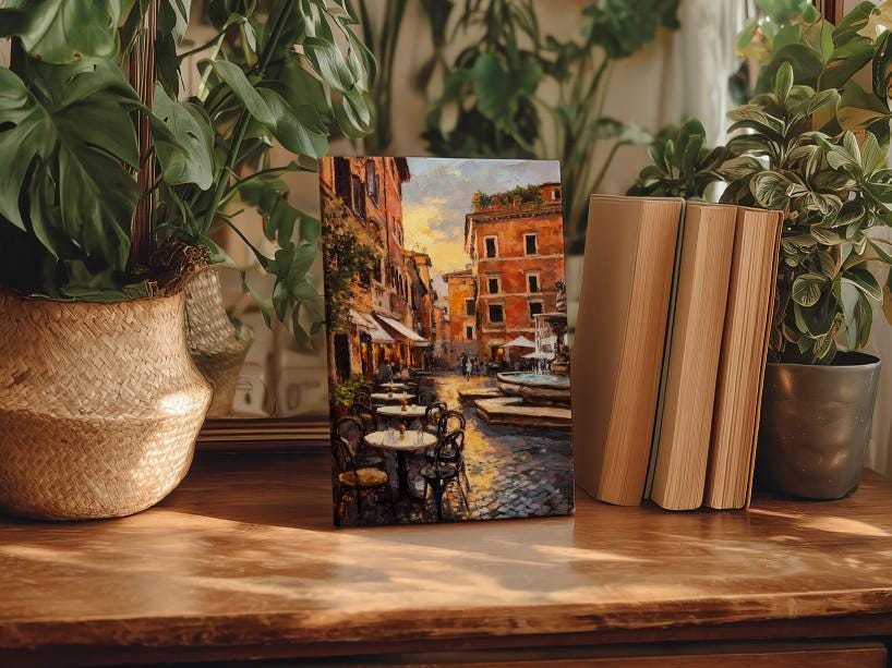 a wooden table with a framed painting of a street scene, surrounded by potted plants and books.