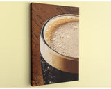 A close-up view of a glass of beer with a foamy head, set against a wooden surface.