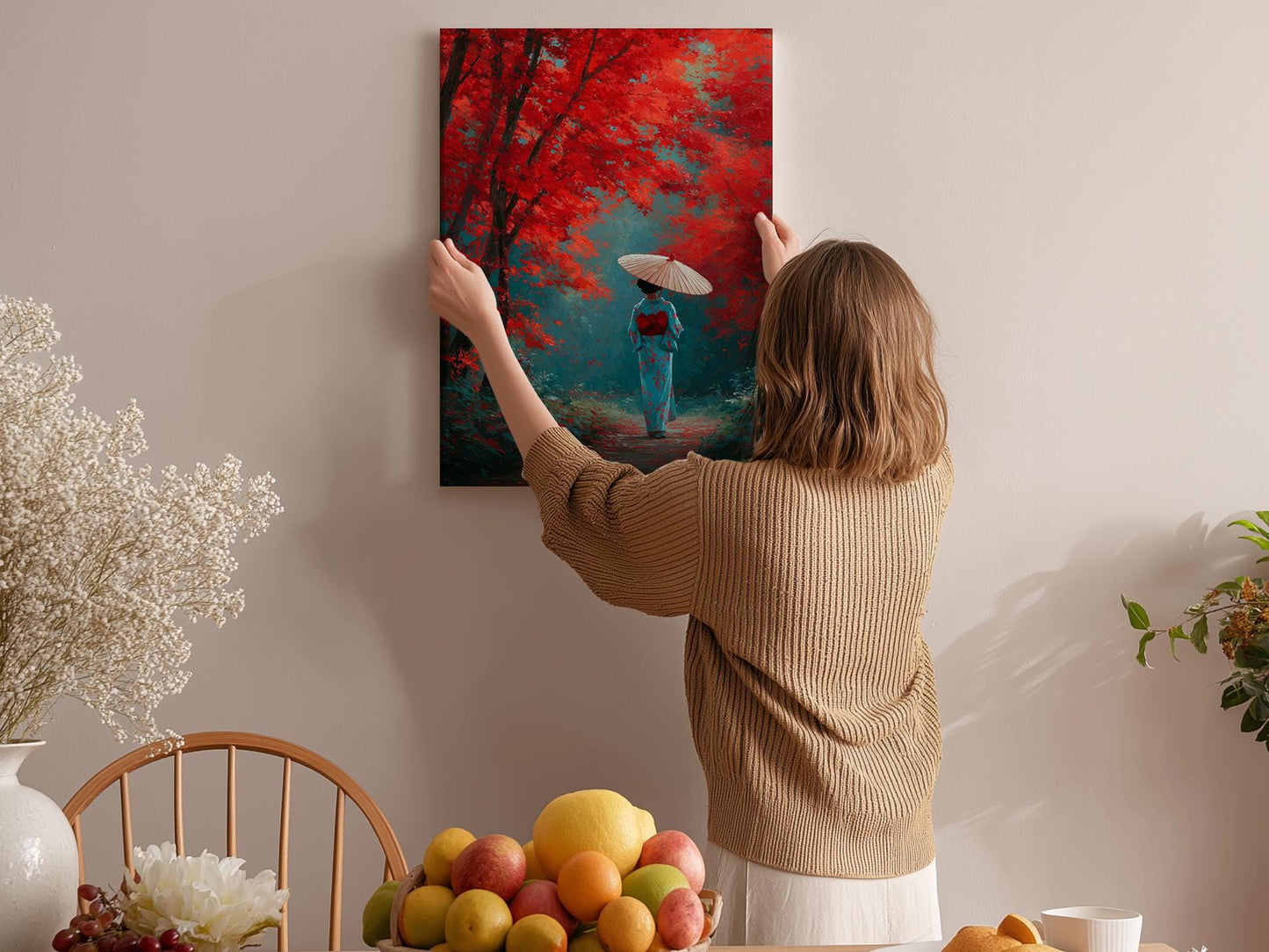 A woman hangs a vibrant painting of a woman in a blue kimono holding an umbrella in a forest, surrounded by a variety of fruits and flowers in a cozy room.