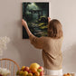 A woman hangs a framed painting of a forest path on a wall in a cozy room with a dining table, chairs, and various fruits.