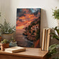 a wooden table with a framed photograph of a coastal cliff at sunset, surrounded by potted plants and books.