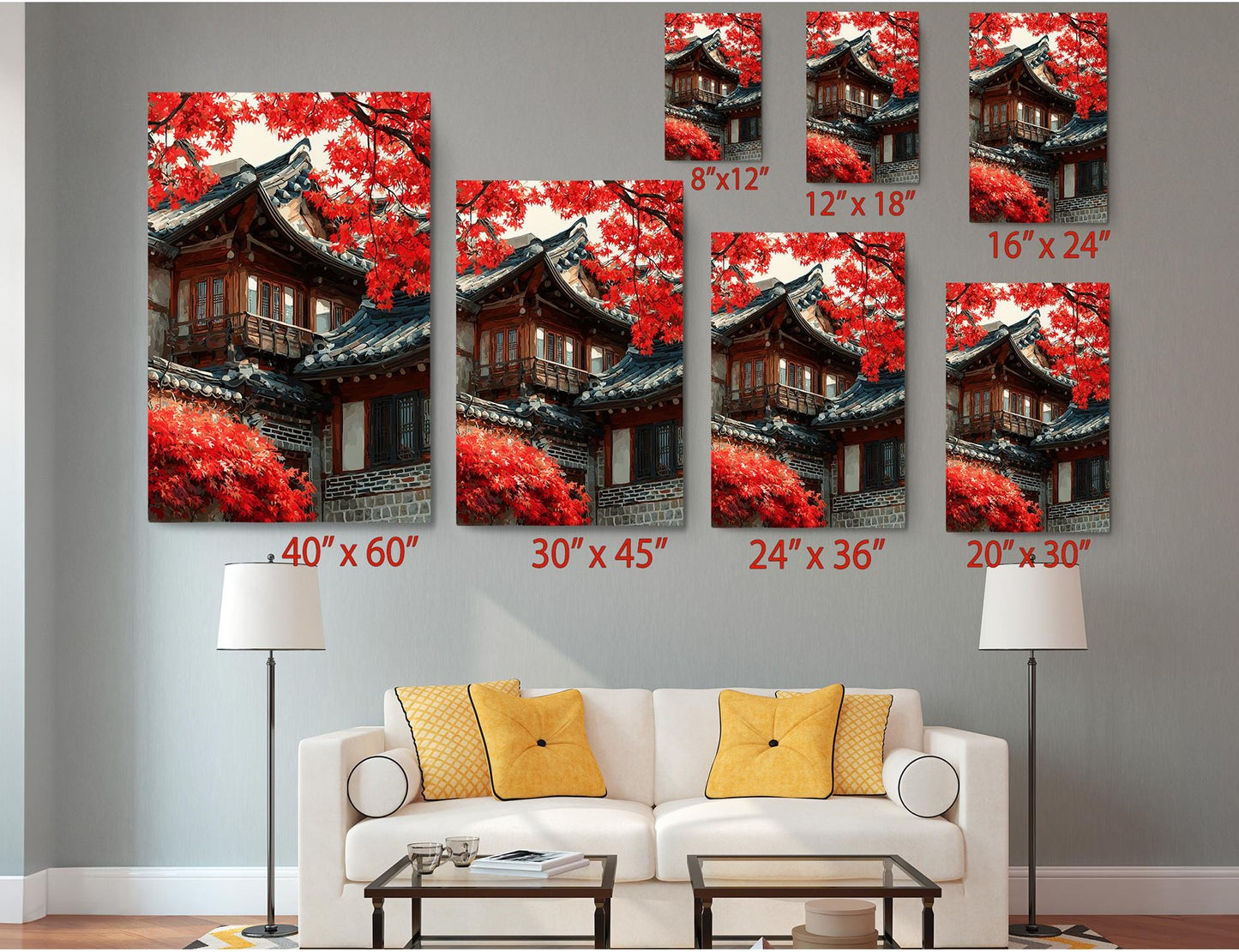 a living room with a white sofa and a coffee table, and there are several framed pictures of traditional Korean houses with red autumn foliage displayed on the wall.