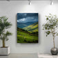 a large landscape painting hanging on a white wall, depicting a pastoral scene with rolling hills, grazing sheep, and a dramatic sky.