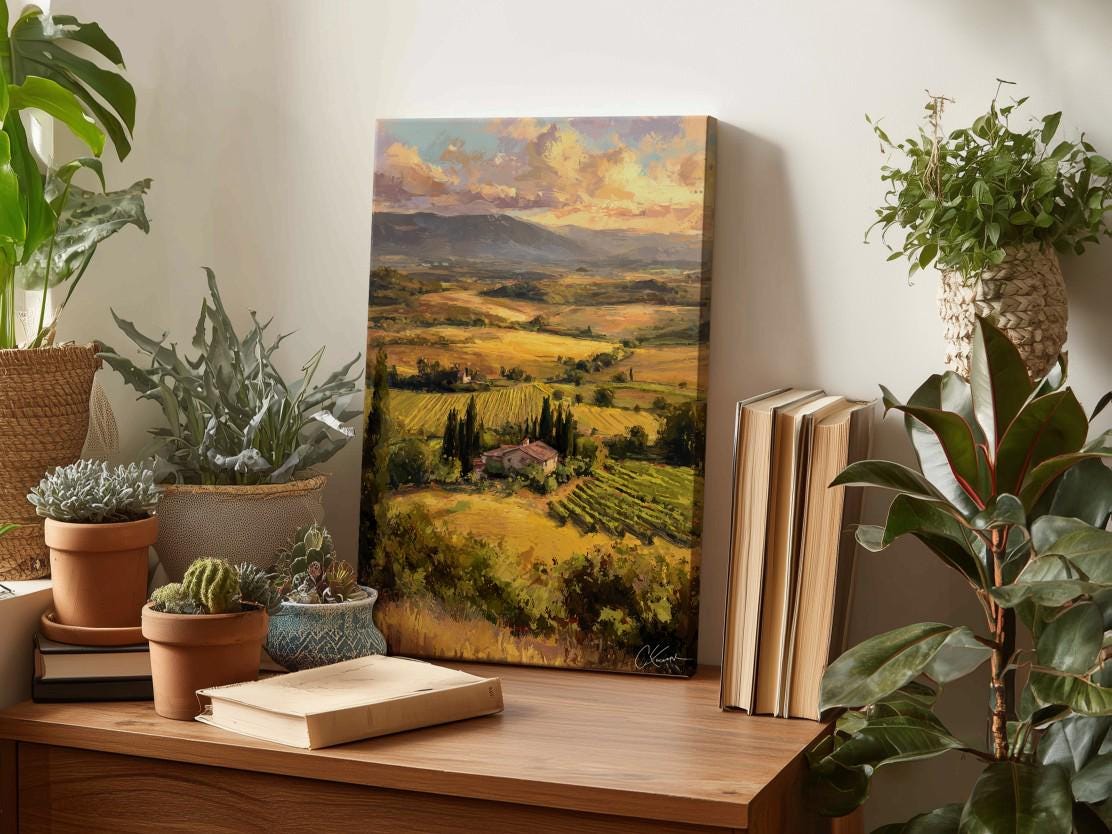 a wooden table with a painting of a countryside landscape, a stack of books, and several potted plants.