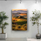 a large landscape painting hanging on a wall, with a potted plant to the left and a potted plant to the right.