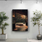 a serene indoor setting with a large potted plant on the left and a framed photograph of a tranquil garden scene on the right.