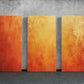 three orange pieces of art on a concrete wall