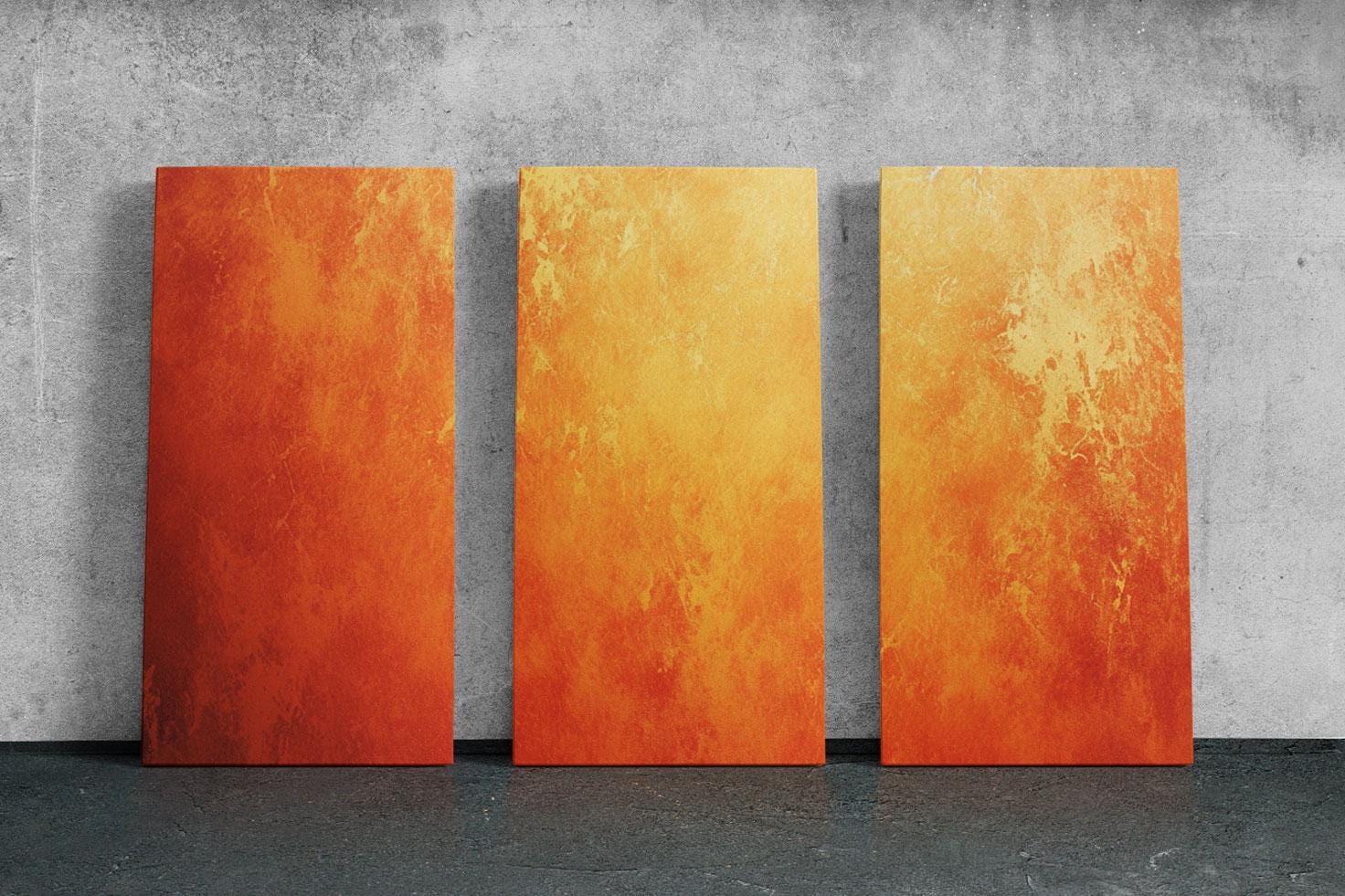 three orange pieces of art on a concrete wall