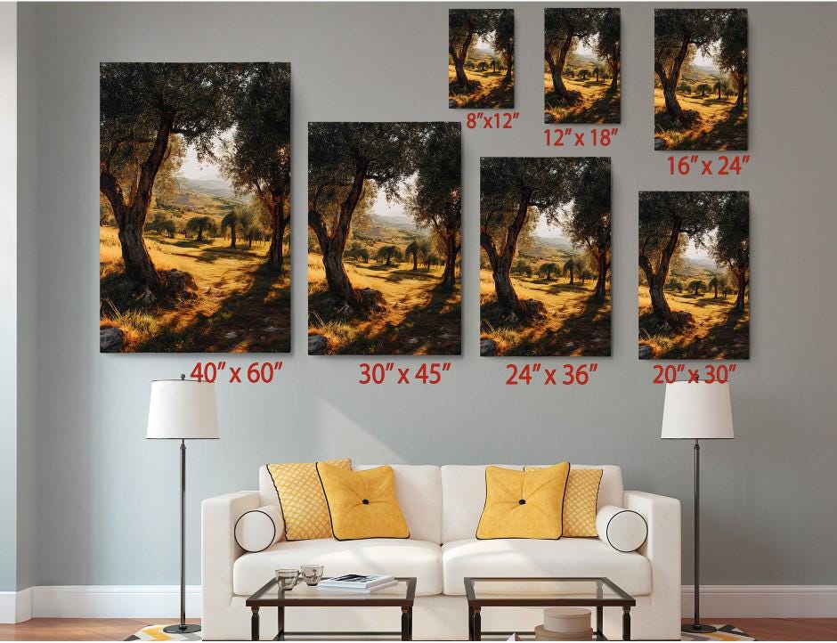 The image is a living room with a white sofa and a coffee table. There are multiple framed landscape photographs of trees displayed on the wall, each with different sizes and orientations. The photographs are arranged in a grid-like pattern, with each one having a specific size and position. The wall has a gray color, and there are two lamps on either side of the sofa.