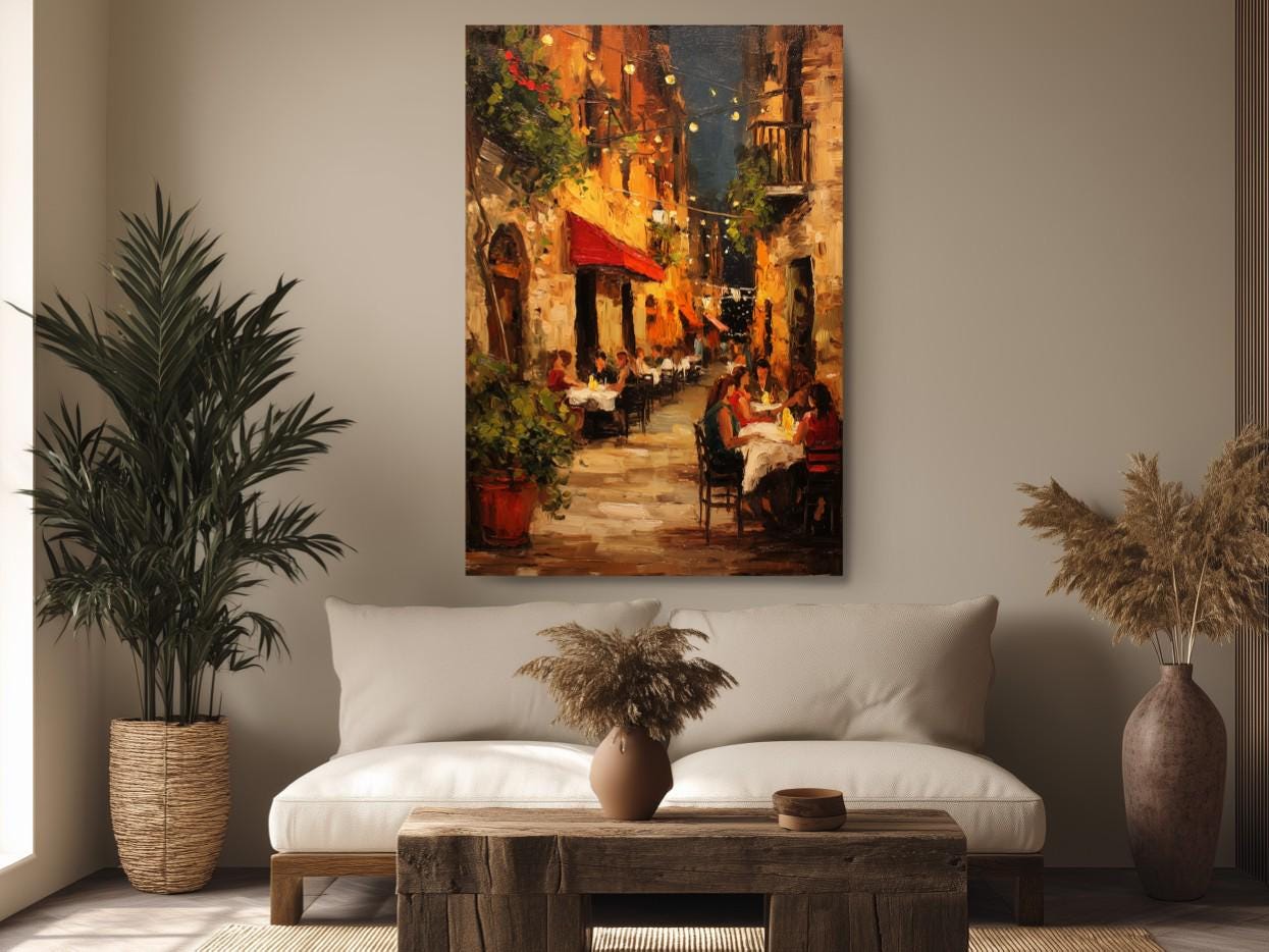 a cozy living room with a large painting of a street scene hanging on the wall. The painting features a restaurant with people dining at tables, surrounded by potted plants and a wooden table. The room is decorated with a white sofa, a wooden coffee table, and a vase with dried flowers.