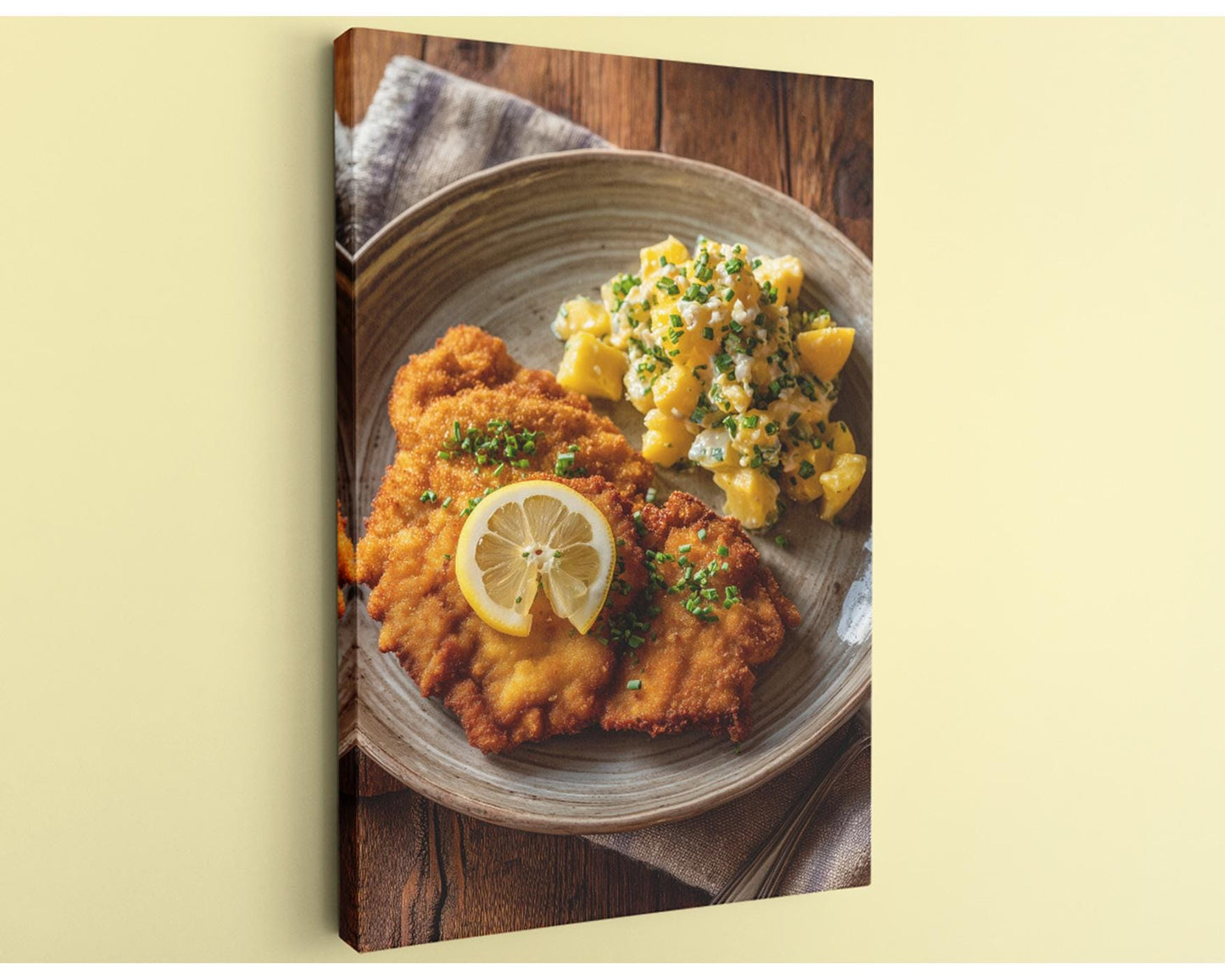 A plate of food, including a piece of fried meat and a side of potato salad, is presented on a wooden surface.