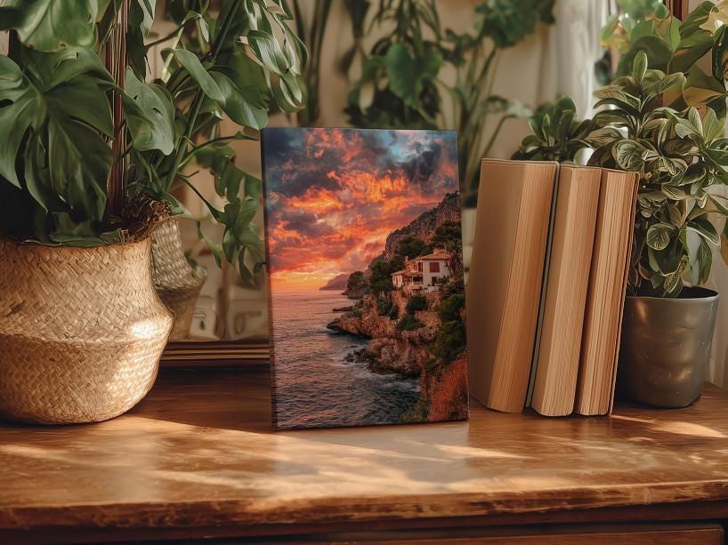 a wooden table with a framed photograph of a coastal landscape, surrounded by potted plants and books.