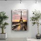 a large painting of the Eiffel Tower hanging on a wall, with a potted plant to the left and a plant to the right.