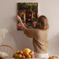 A woman hangs a framed picture of a restaurant on a wall in a cozy, homely setting.