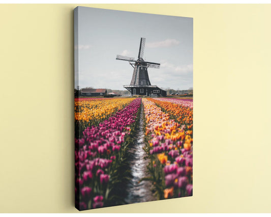 A large windmill stands in a field of colorful tulips, creating a picturesque scene.