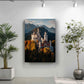 a large painting of a castle on a mountain, with a backdrop of trees and mountains. The painting is hung on a white wall, and there are two potted plants in the foreground, one on the left and one on the right.