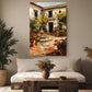 a cozy living room with a large painting of a Spanish courtyard hanging on the wall above a white sofa. The painting depicts a courtyard with a fountain, surrounded by potted plants and flowers, creating a serene and inviting atmosphere.