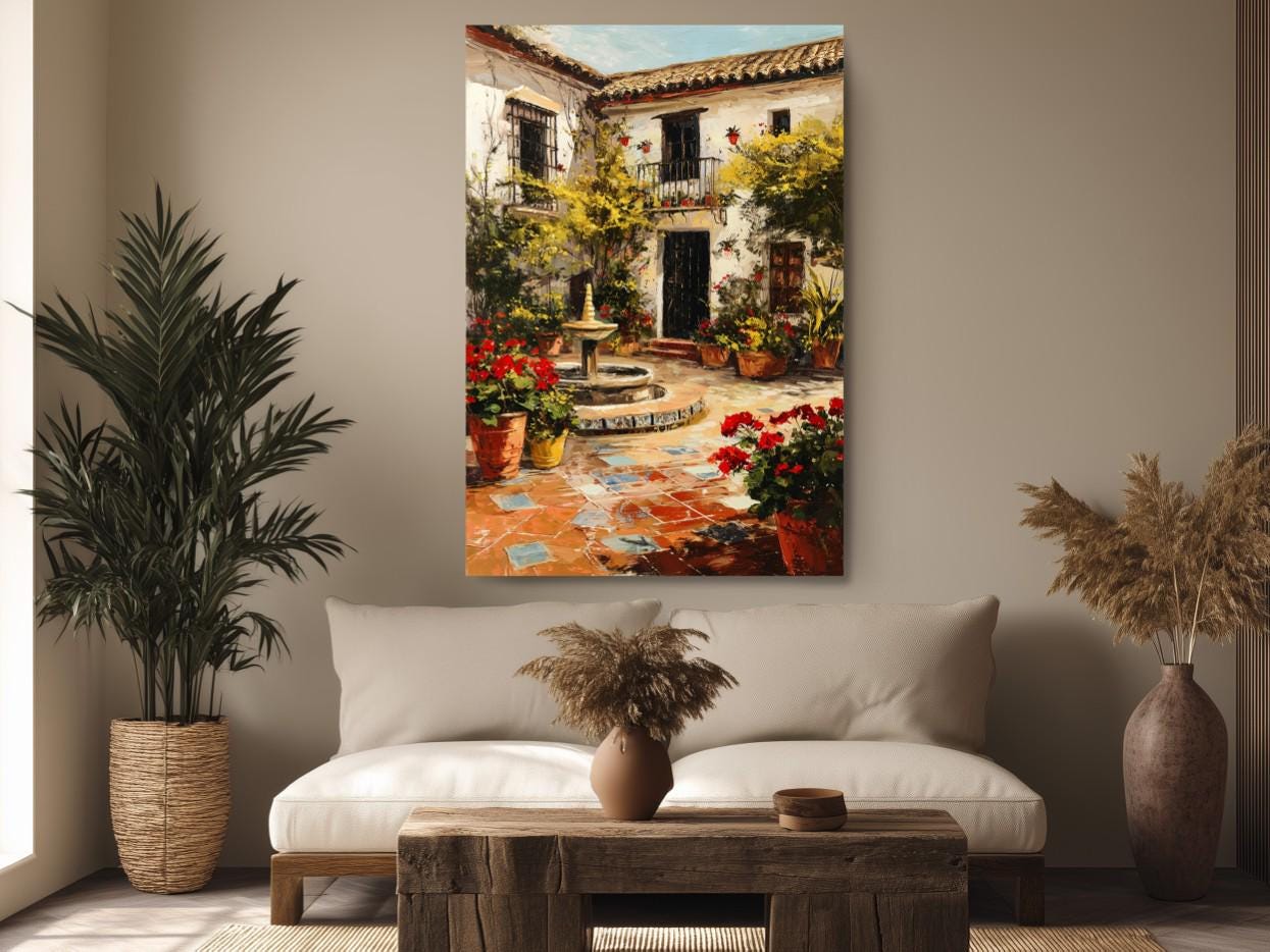 a cozy living room with a large painting of a Spanish courtyard hanging on the wall above a white sofa. The painting depicts a courtyard with a fountain, surrounded by potted plants and flowers, creating a serene and inviting atmosphere.
