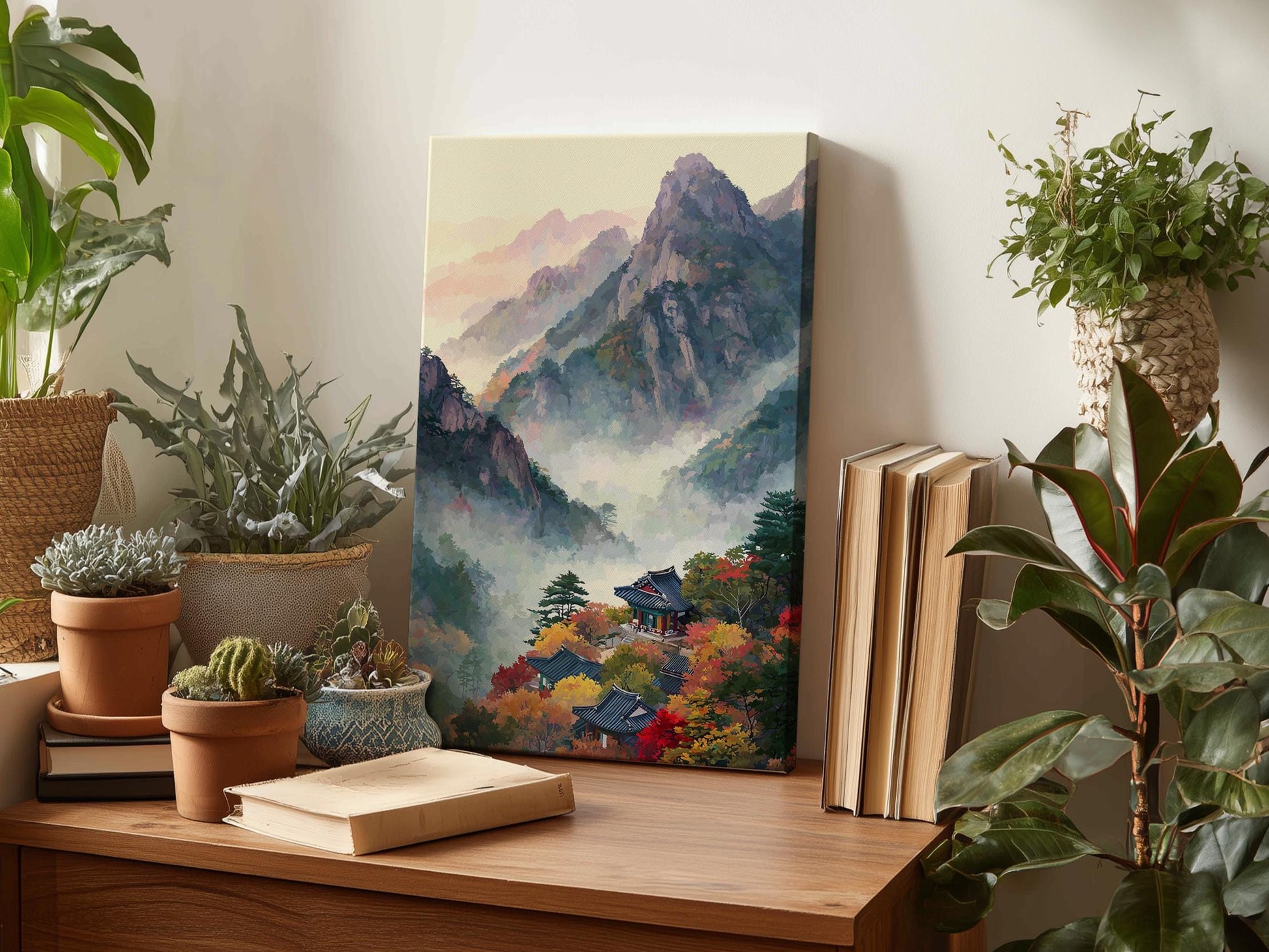 a wooden desk with a painting of a mountainous landscape, a stack of books, and several potted plants.