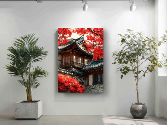 a large, colorful painting of a traditional Korean building with red leaves on its roof, hanging on a white wall. To the left of the painting, there is a potted plant, and to the right, there is another potted plant.