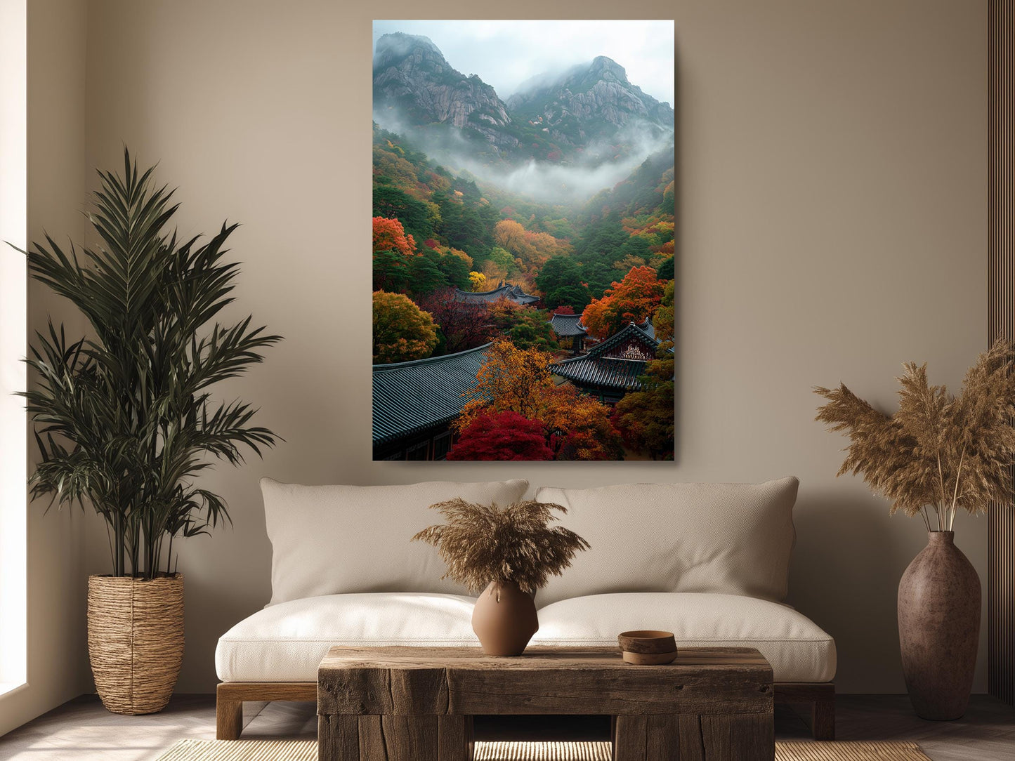 a living room with a large painting of a mountainous landscape hanging on the wall. The painting depicts a serene mountain scene with colorful autumn foliage. The room is decorated with potted plants, a wooden coffee table, and a vase, creating a cozy and inviting atmosphere.