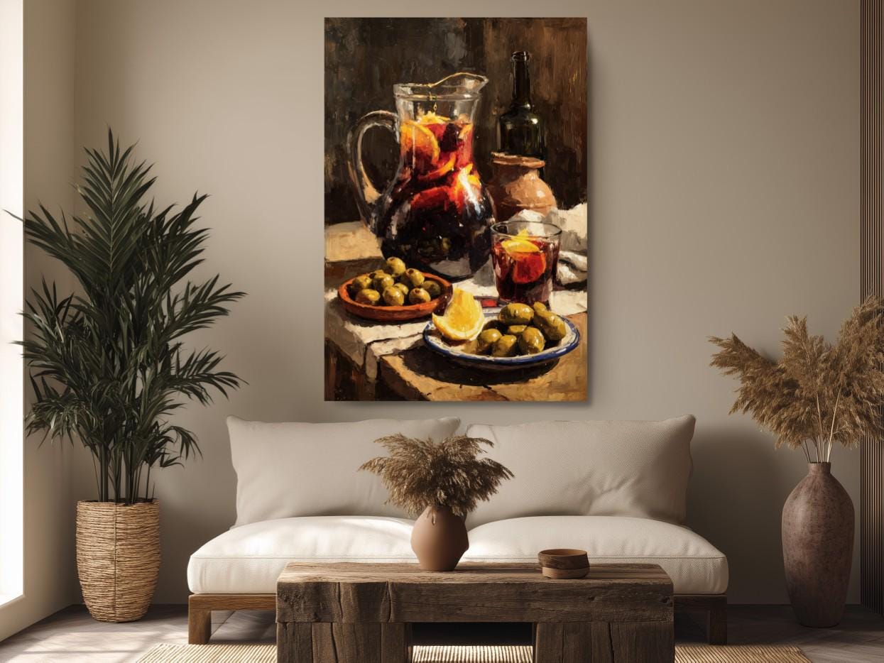 a cozy living room with a large painting of a table set with food and drinks hanging on the wall. The painting features a pitcher of red liquid, a plate of olives, a bowl of fruit, and a glass of wine. The room is decorated with potted plants, a wooden coffee table, and a vase of dried flowers, creating a warm and inviting atmosphere.